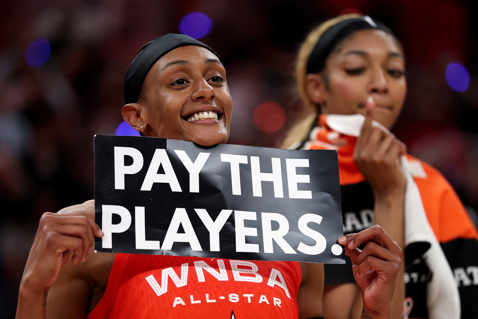Brittney Sykes of the Washington Mystics holds a "Pay the Players" sign next to Angel Reese of the Chicago Sky following the AT&T WNBA All-Star Game at Gainbridge Fieldhouse on July 19, 2025.