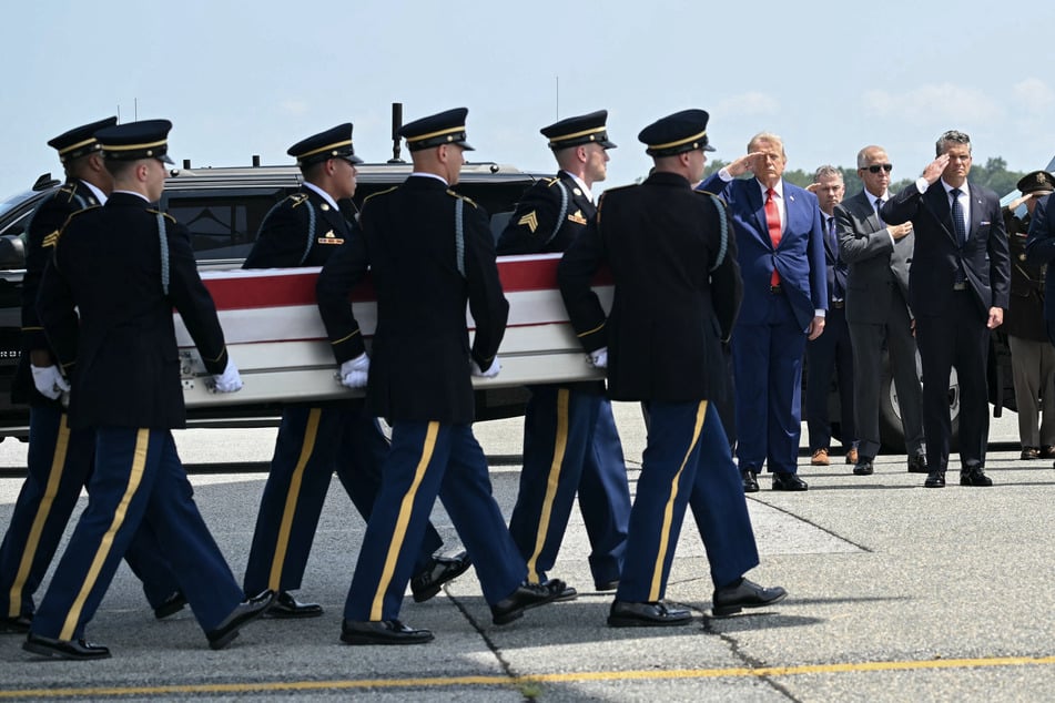 President Donald Trump (l) and Defense Secretary Pete Hegseth (r) salute as the body of a soldier killed in the US' war on Iran is returned to the US.