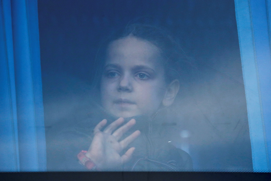 A girl looks through the bus window as civilians evacuated from the Azovstal steel plant in Mariupol arrive at a temporary accommodation centre in the village of Bezimenne.
