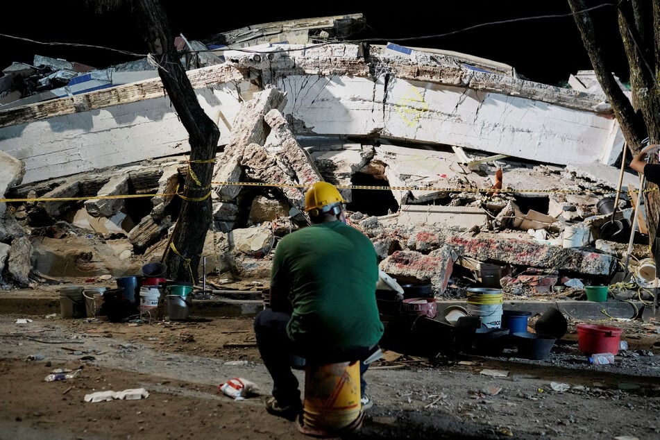 A man sits near debris at the Torres de Limonar building in the aftermath of an earthquake, in Cali, Colombia, on August 11, 2026.