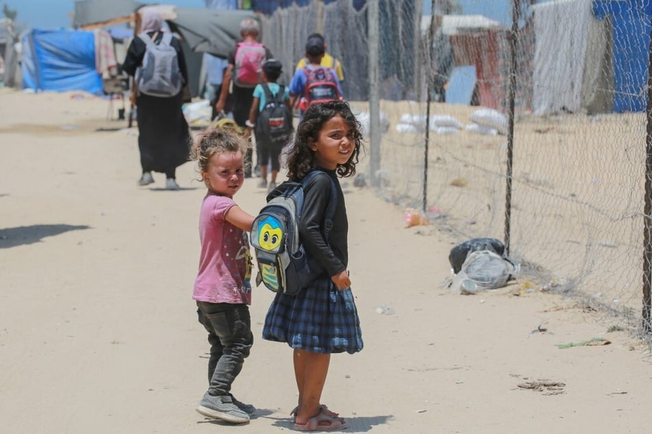 Displaced Palestinian children look on as people evacuate the al-Mawasi area on the outskirts of southwestern Khan Younis in the southern Gaza Strip.