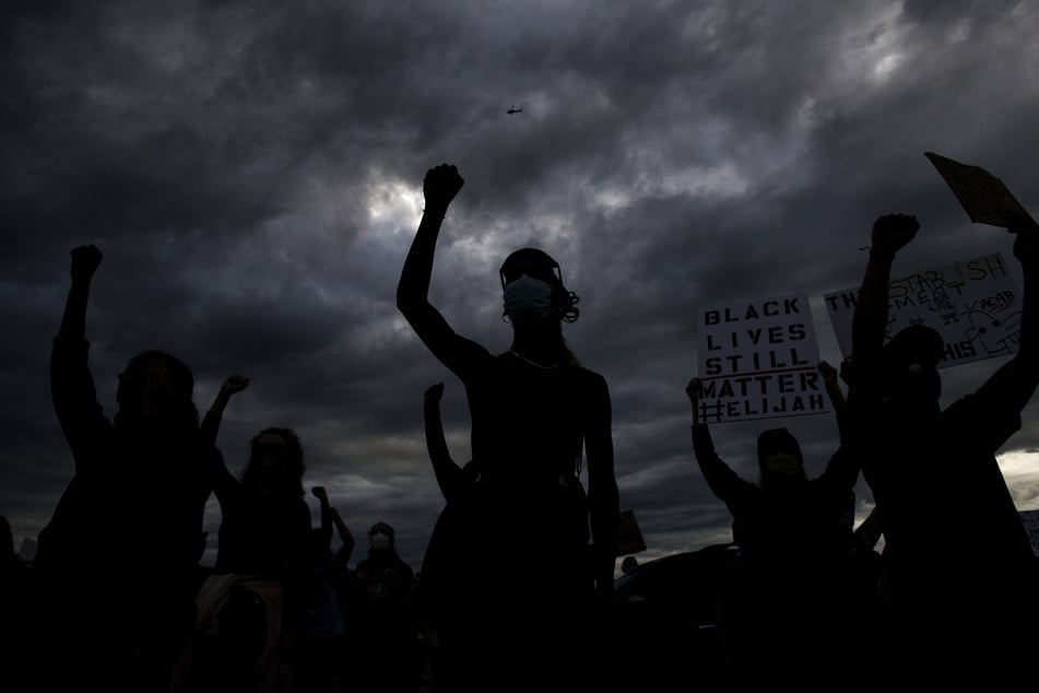 People hold their fists in the air in protest over the death of Elijah McClain, whose case became a clarion call in the Black Lives Matter movement.