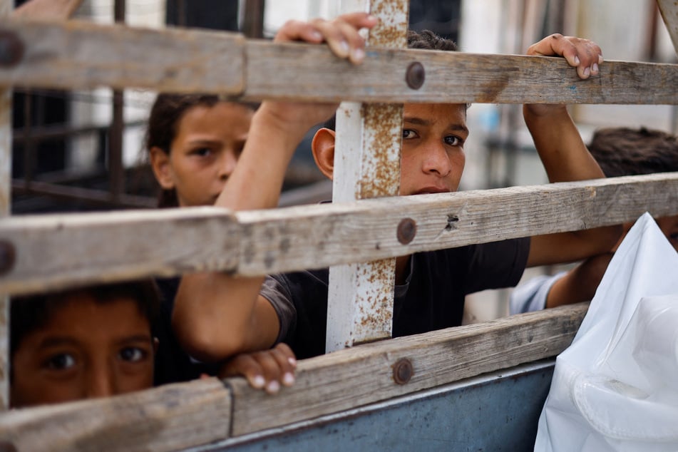 Children look into a vehicle carrying the bodies of Palestinians killed in an Israeli strike, during a funeral in Rafah.