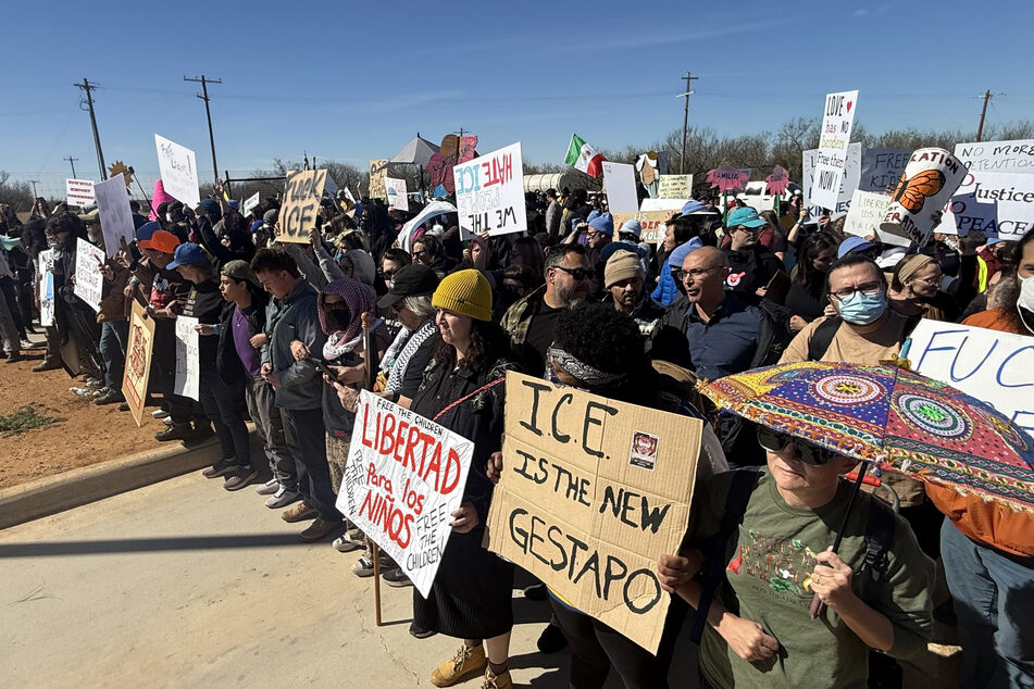 People hold anti-ICE signs during a demonstration and vigil outside the South Texas Family Residential Center in Dilley, Texas, on January 28, 2026.