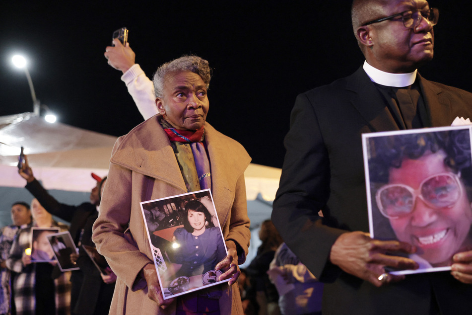 Community faith leaders hold photos of Dalyce Curry (r.) and Patricia McKenna, two of the 19 deceased victims of the Eaton Fire, before a moment of silence at a community commemoration event in Altadena, California, on January 7, 2026.