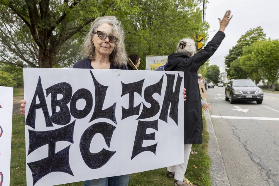 A woman holds an "Abolish ICE" sign during a protest in Newburyport, Massachusetts, on August 22, 2026.
