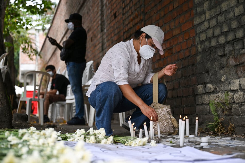 Volunteer Gloria Alegrias lights a candle at an improvised memorial for victims of the earthquake outside the Palmira morgue in Valle del Cauca department, Colombia, on August 14, 2026.