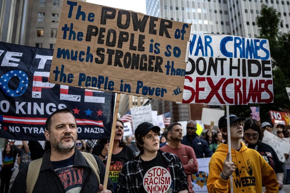 People raise signs as they march in a No Kings: Vote Early demonstration in Houston, Texas, on October 17, 2026.