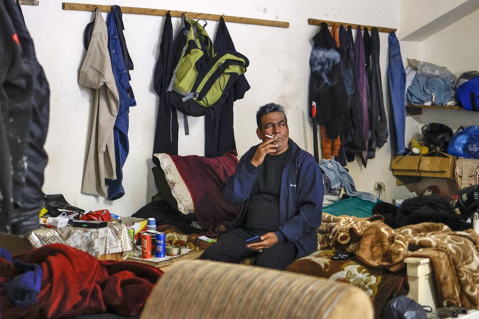 A Palestinian man from Gaza who has been stranded in the occupied West Bank smokes a cigarette as he sits in a locker room converted to an encampment at Nablus Football Stadium on May 7, 2026.