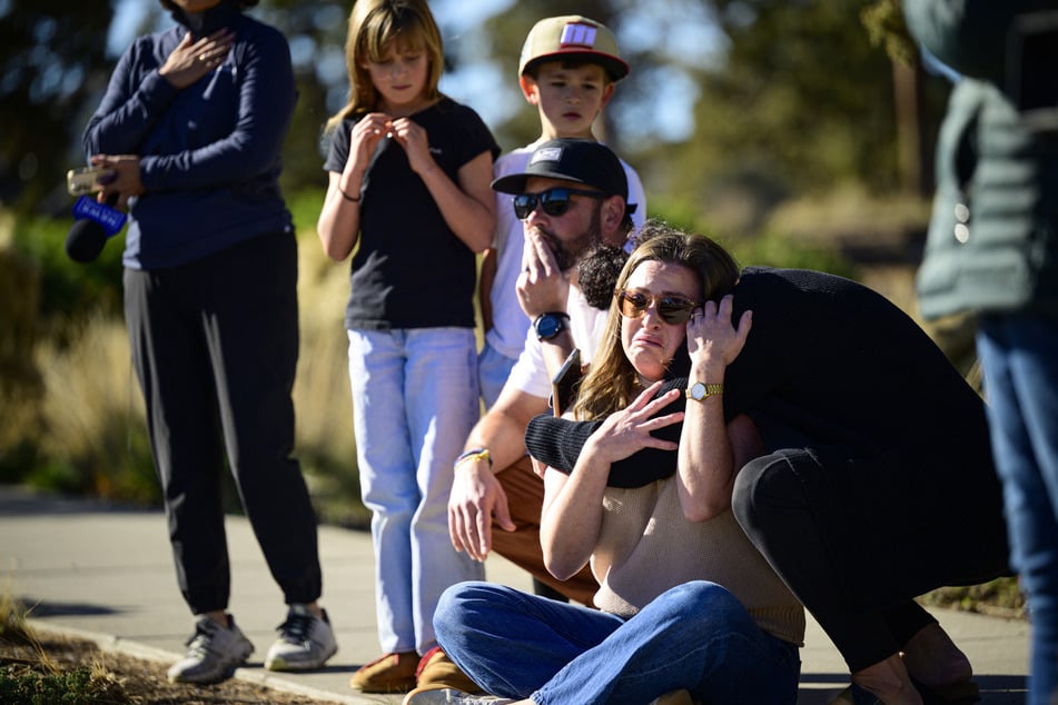 Community members grieve at the site of a makeshift memorial in front of Silver Rail Elementary School on Friday. The school remains 