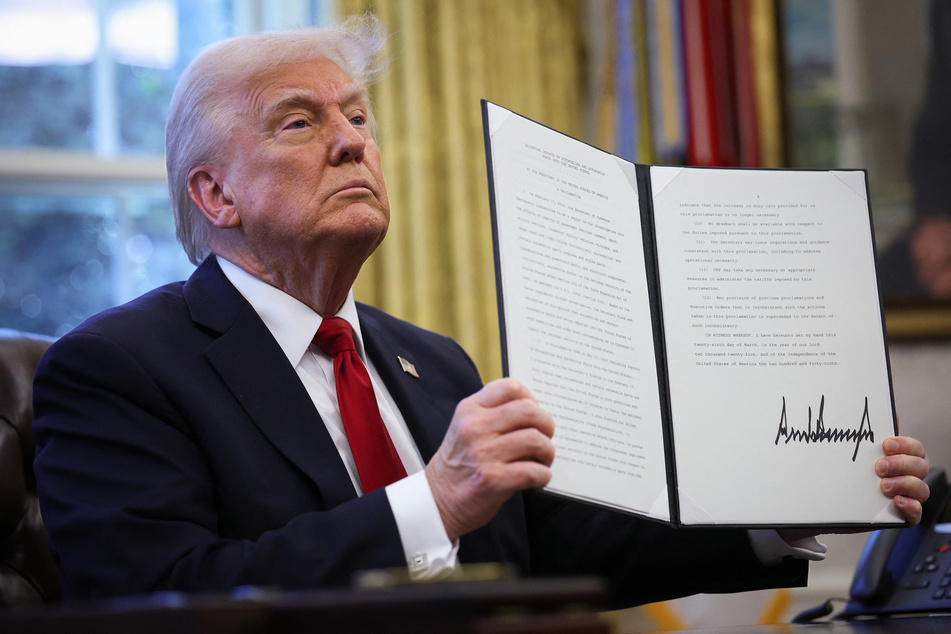 US President Donald Trump displays a signed an executive order announcing 25% tariffs on all foreign-made cars in the Oval Office of the White House on Wednesday in Washington, DC.