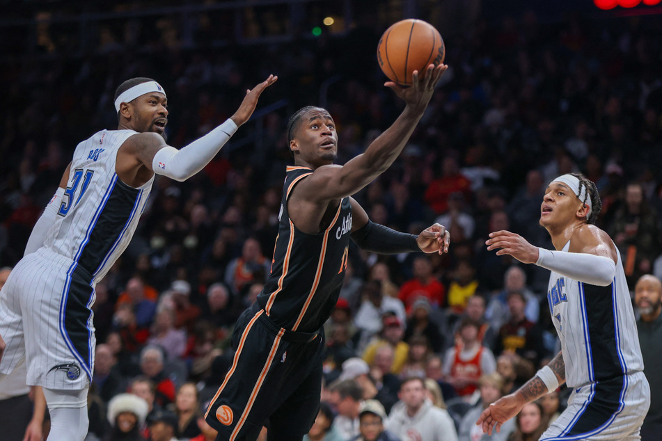 Atlanta Hawks forward AJ Griffin (c.) takes a shot as the Orlando Magic's Terrence Ross (l.) and Paolo Banchero look on.