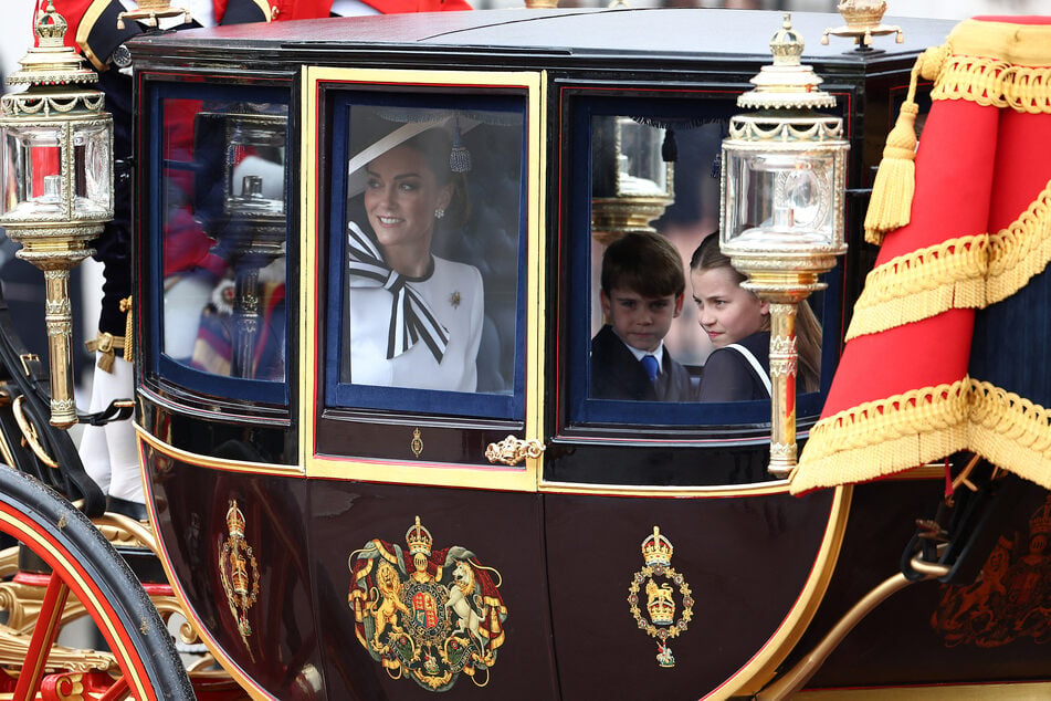 While Prince William accompanied the parade on horseback, Kate Middleton (l.) and her three children rode to and from the parade grounds in a carriage.