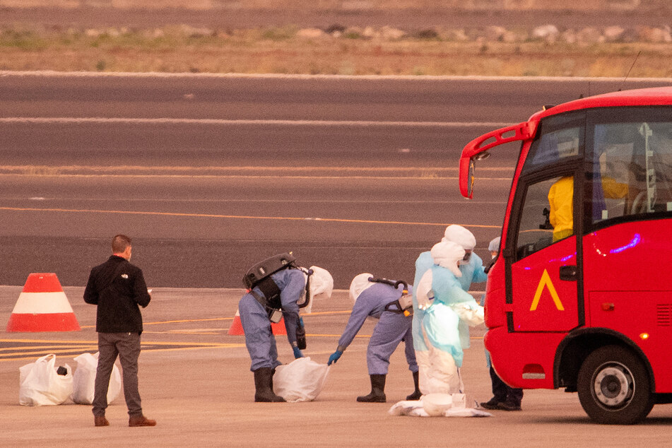 People in hazmat suits as passengers board a plane bound for the US with passengers evacuated from the hantavirus-stricken cruise ship MV Hondius.