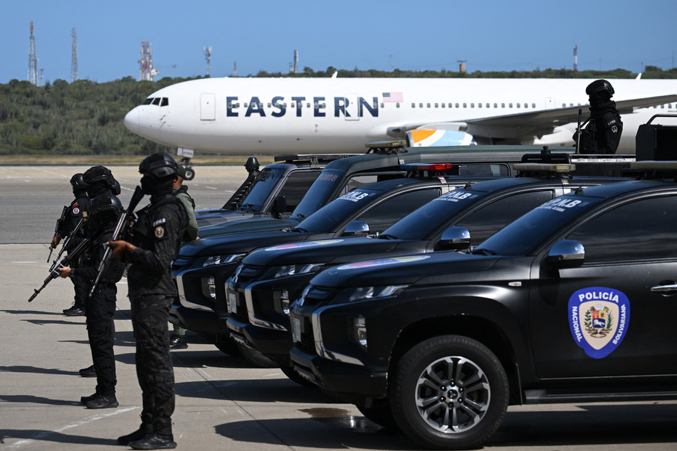 Bolivarian National Police officers stand guard while an Eastern Airlines plane carrying Venezuelan migrants deported from the US lands at Simon Bolivar International Airport in Maiquetia, Venezuela, on Friday.