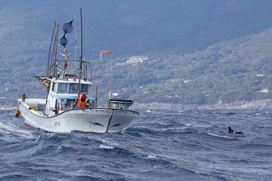 An object believed to belong to the US military aircraft V-22 Osprey that crashed into the sea floats next to a fishing boat off Japan's Yakushima Island.
