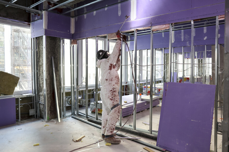 A worker paints at 77 Water Street, a former office building being transformed into luxury rental apartments in the Financial District of New York, on April 10, 2026.