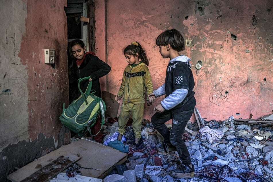 Children inspect items in the rubble in a room overlooking a building destroyed by Israeli bombardment in Rafah in the southern Gaza Strip on December 24, 2023.