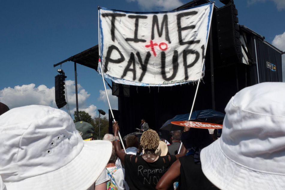 A participant at the 60th Anniversary March on Washington calls for reparations for Black Americans.