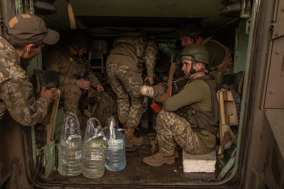 Ukrainian soldiers with their weapons wait inside a US-made M113 armored personnel carrier to depart for the front in an undisclosed area, in the eastern Donetsk region, on August 5, 2024, amid the Russian invasion of Ukraine.