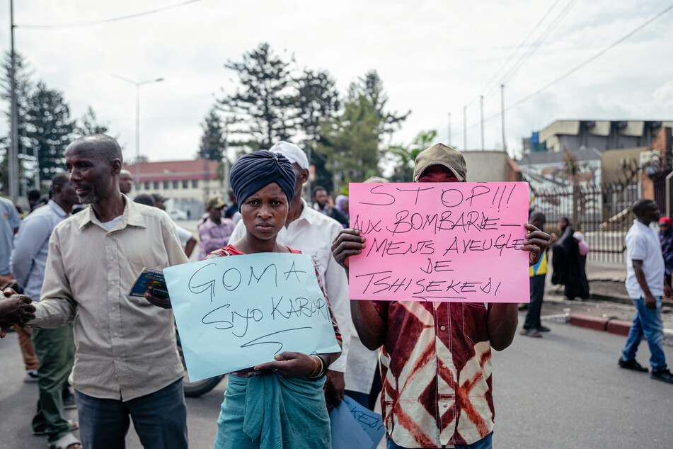 Demonstrators hold signs as they march during a protest denouncing air strikes in areas controlled by the Rwanda-backed M23 militia in Goma, Democratic Republic of the Congo, on March 12, 2026.