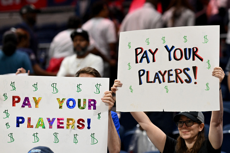 Fans hold up "Pay Your Players" signs during the game between the Washington Mystics and the Phoenix Mercury at Carefirst Arena on July 27, 2025.
