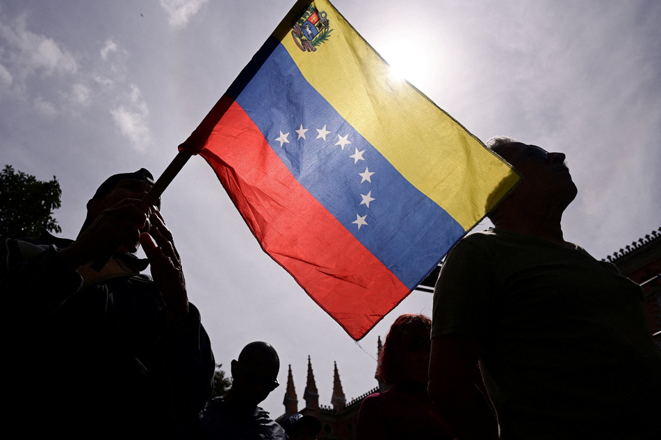 A demonstrator waves a Venezuelan flag as supporters of President Nicolás Maduro gather in Caracas on January 3, 2026.
