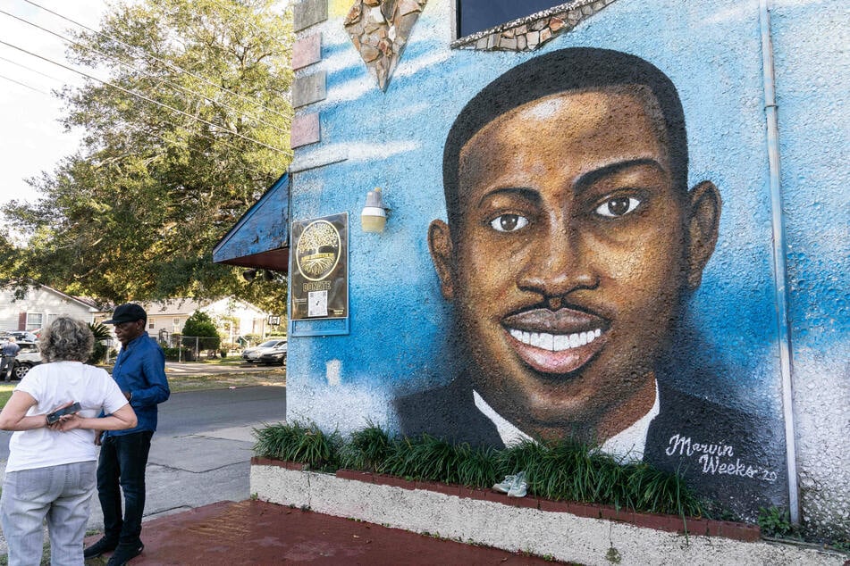Artist Marvin Weeks chats with a visitor next to his mural of Ahmaud Arbery painted on the side of the Brunswick African American Cultural Center in Georgia.