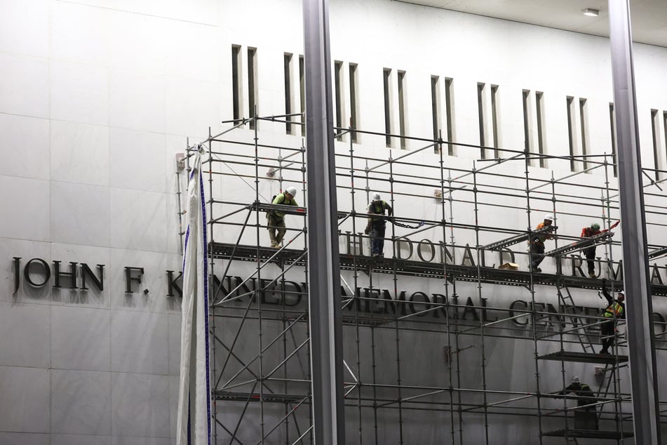Workers build scaffolding near the signage for the "Donald J. Trump and John F. Kennedy Memorial Center for the Performing Arts" in Washington, DC, early on June 13, 2026.