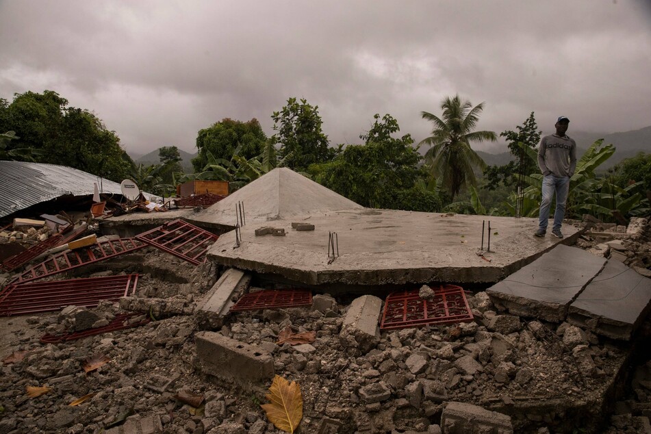 A man observes the wreckage of buildings while the rain falls during Tropical Storm Grace.