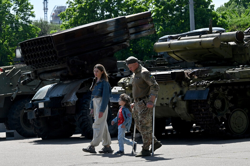 A wounded Ukrainian serviceman and his family walk next to military vehicles displayed at the National Museum of the History of Ukraine in the Second World War in Kyiv on May 9, 2026