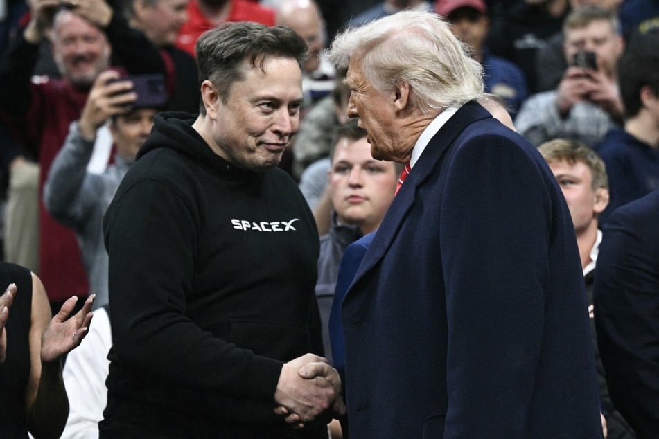 Elon Musk and President Donald Trump (r) shake hands during the men's NCAA wrestling competition at the Wells Fargo Center in Philadelphia, Pennsylvania, on March 22, 2025.