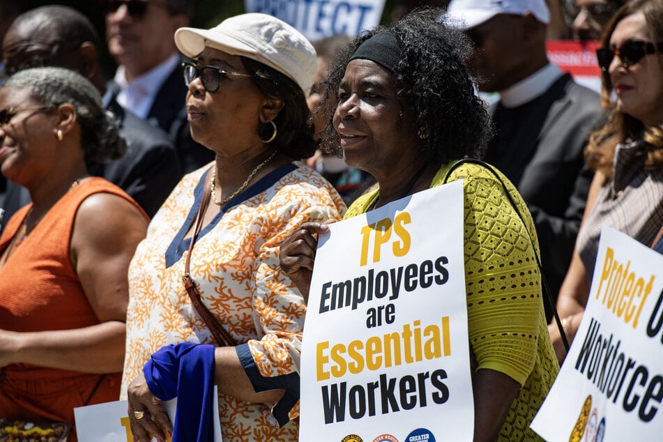 People hold signs at a rally calling on Congress to restore Temporary Protected Status for Haitians, in Boston, Massachusetts, on July 23, 2026.