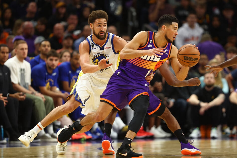 Phoenix Suns guard Devin Booker moves the ball against Golden State Warriors guard Klay Thompson in the second half at Footprint Center.