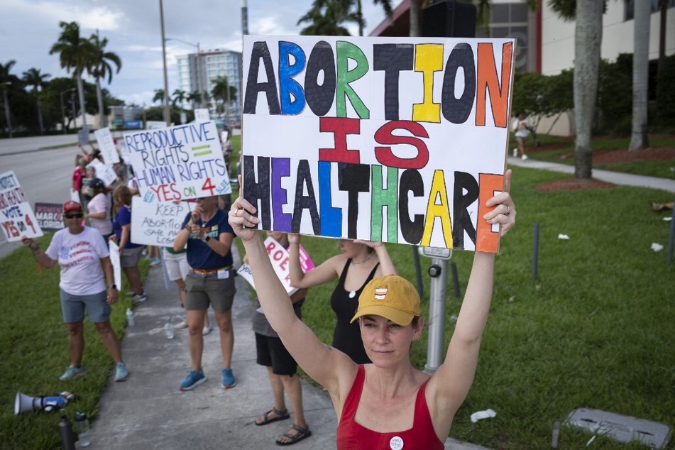 Demonstrators hold up signs during a pro-abortion rights rally on the second anniversary of the Supreme Court ruling to overturn Roe v. Wade, in West Palm Beach, Florida.