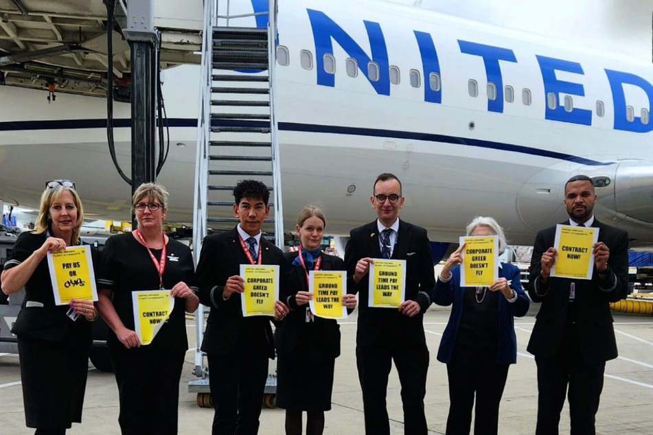 United Flight attendants hold up signs reading "Pay Us or Chaos" and "Corporate Greed Doesn't Fly" after landing in London, UK.