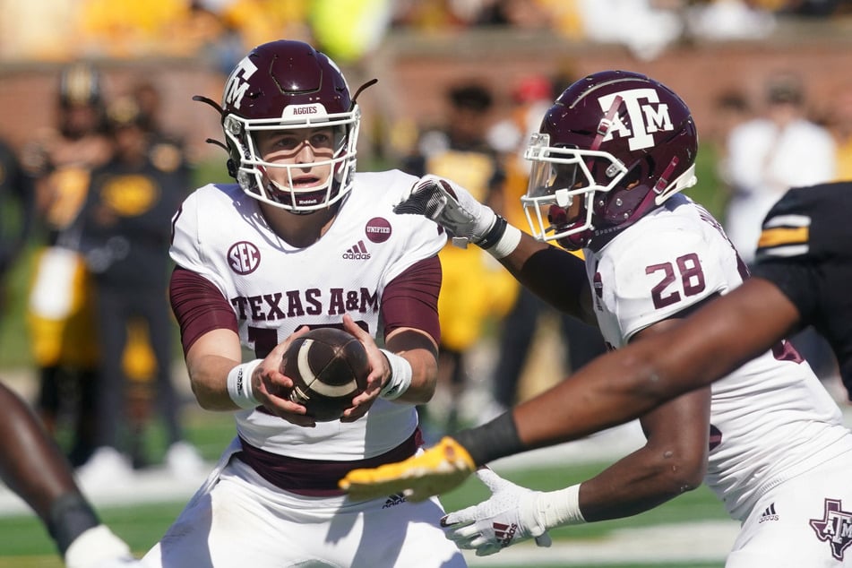 Texas A&M quarterback Zach Calzada (l.) hands the football off to running back Isaiah Spiller (r.).