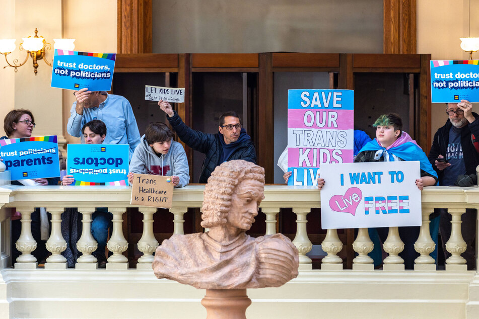 Opponents of a bill that would prevent medical professionals in Georgia from giving transgender minors certain hormones or surgical treatment protest in the state Capitol.