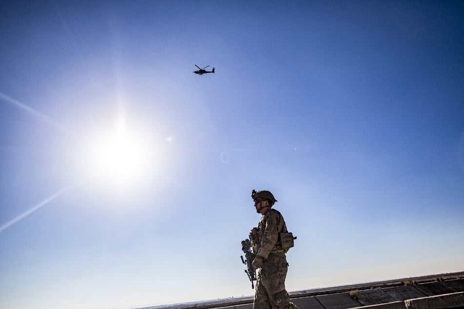 A US AH-64 Apache attack helicopter flies above US soldiers patrolling along the frontlines between areas held by the Syrian Democratic Forces and Turkish-backed fighters.