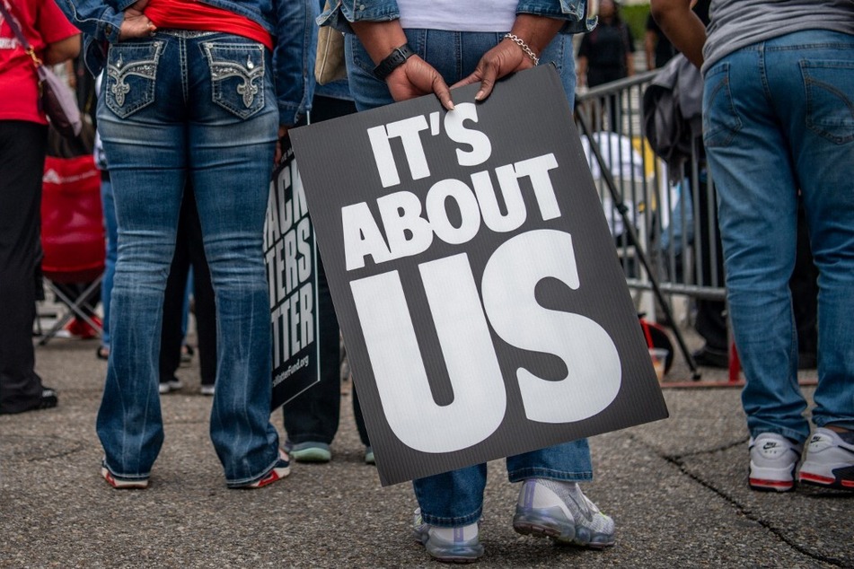 Protesters hold signs reading "It's About Us" while commemorating the 1965 Selma-to-Montgomery marches.
