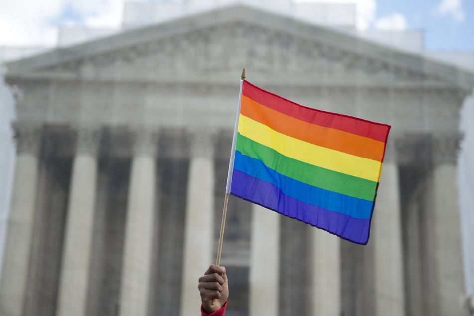 An LGBTQ+ rights activist waves a rainbow flag in front of the US Supreme Court in Washington DC.