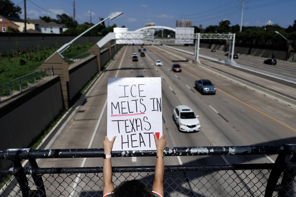 A person holds a sign on a bridge over a highway in Houston reading "ICE Melts in Texas Heat!" ICE agents have been accused of deliberately running over a Mexican man in the Texas metropolis.