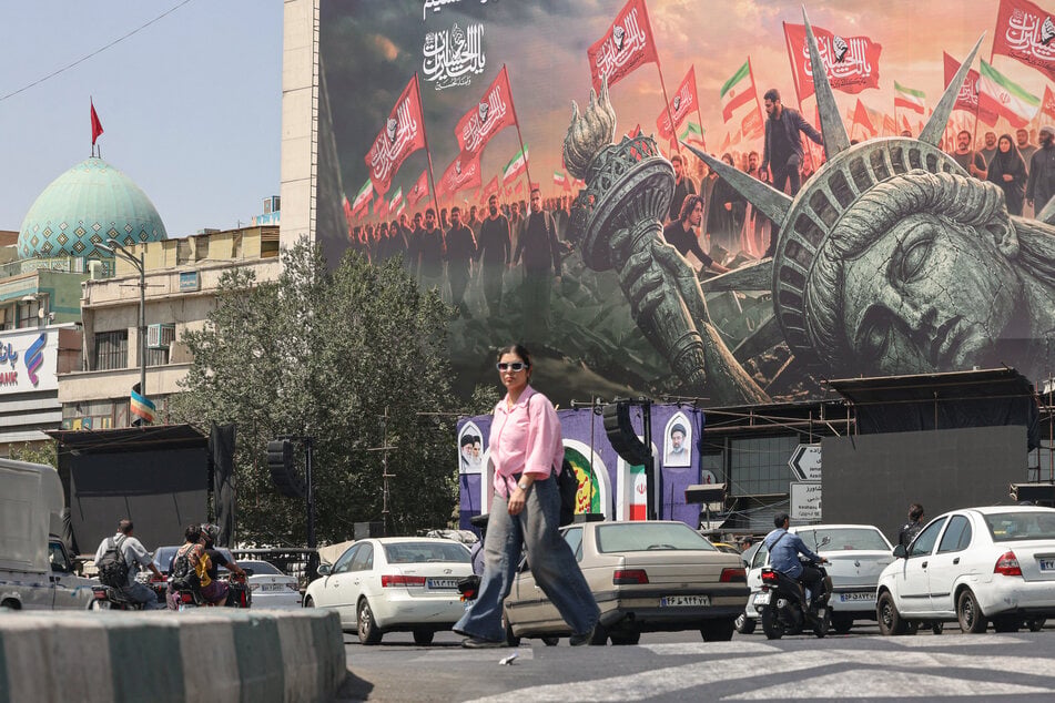 People walk past an anti-US billboard at Enghelab Square in central Tehran on September 2, 2026. The US and Iran have launched new strikes as the war continues with no end in sight.