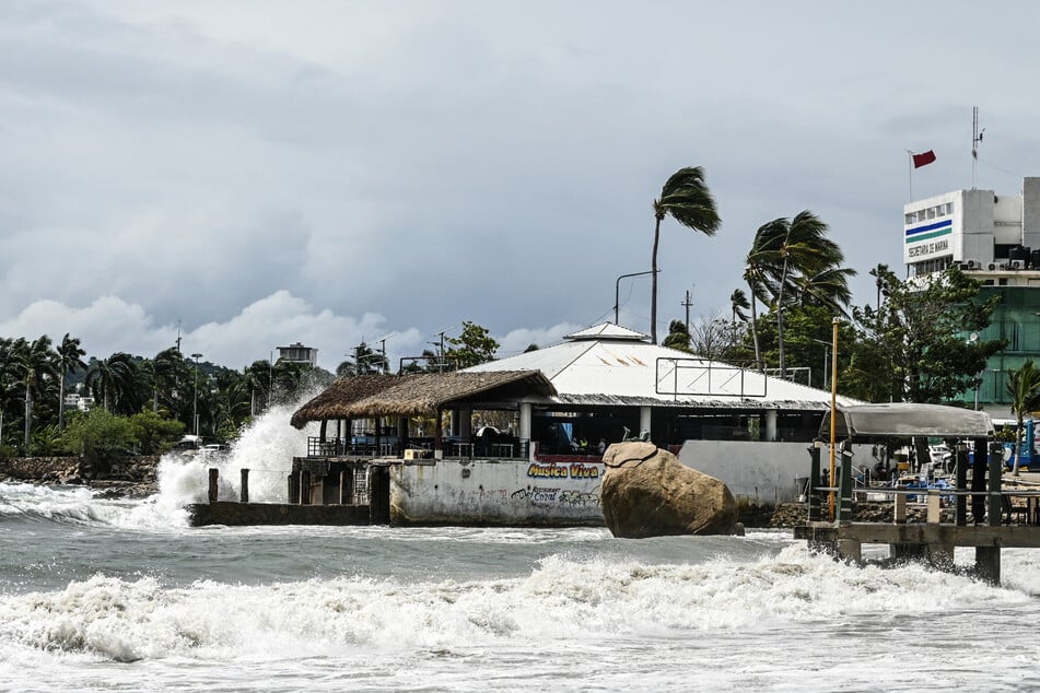 High waves crash against the waterfront as a red flag flies in Acapulco, Mexico, on September 28, 2026, warning vessels not to sail ahead of the arrival of Tropical Storm Rachel. At least eight people have died in the storm, according to Mexican authorities. 