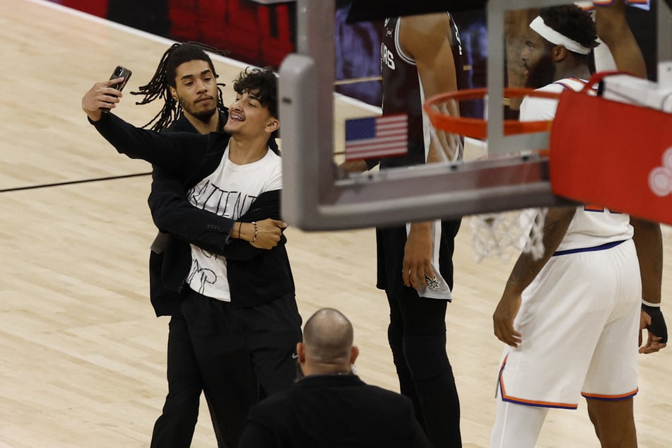 A fan runs onto the court and is met by security staff in the second half during game one of the 2026 NBA Finals at Frost Bank Center.