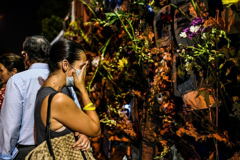 Distraught people mourning near the impromptu shrine to the victims of the tower collaps