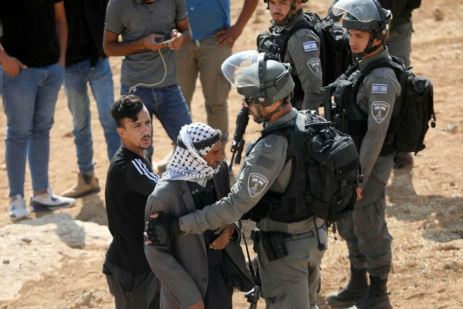 Israeli security forces stand guard as a bulldozer prepares to destroy a Palestinian home in Hebron.