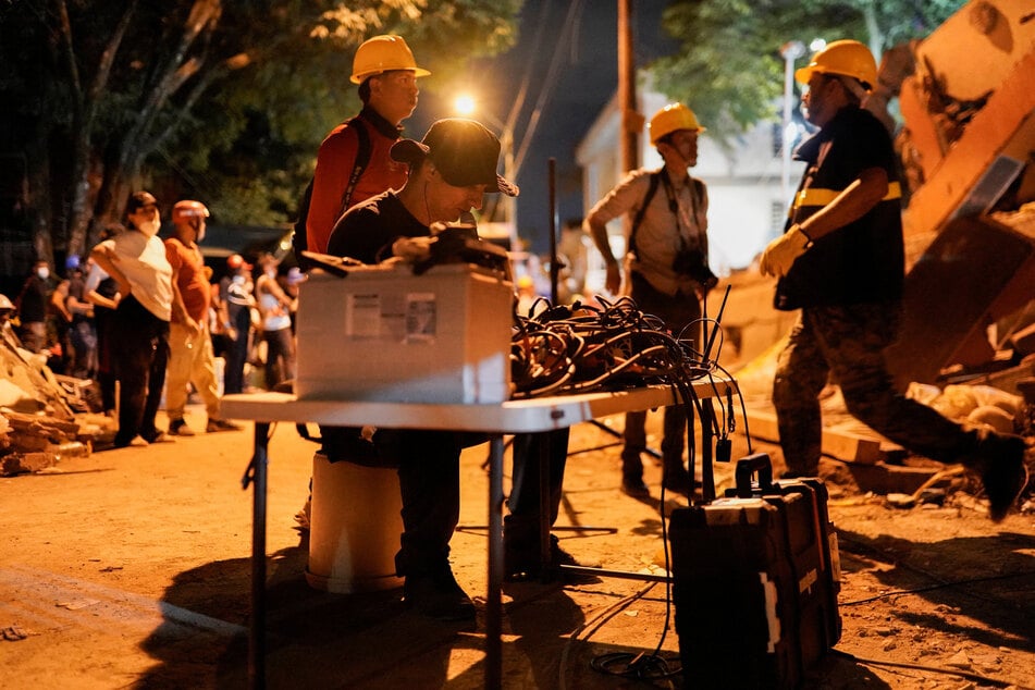 A member of the rescue personnel uses a geophone to detect survivors beneath the rubble at the Torres de Limonar building in the aftermath of an earthquake, in Cali, Colombia, on August 11, 2026.
