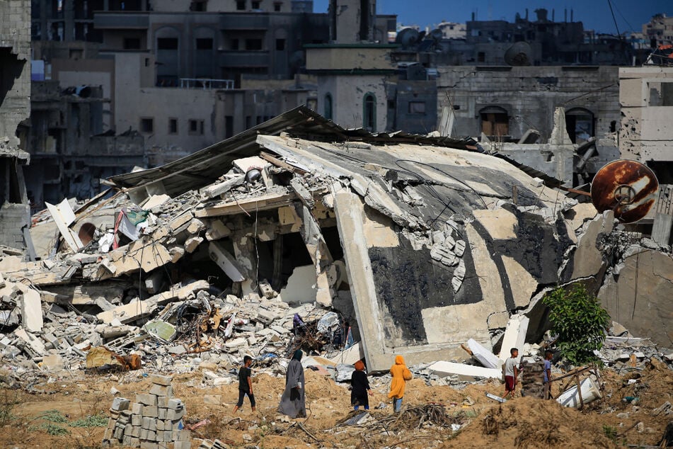Palestinian women and boys walk towards destroyed buildings as some residents return to the city of Khan Yunis on Sunday.