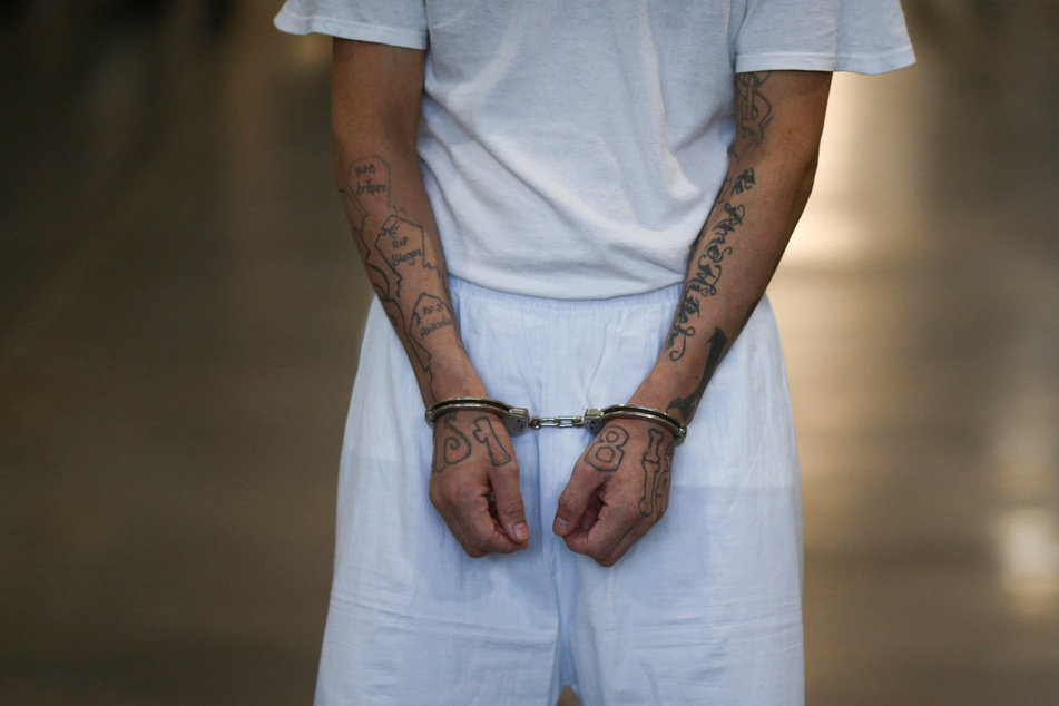 A deported migrant is pictured in handcuffs at El Salvador's Terrorism Confinement Center prison in Tecoluca.